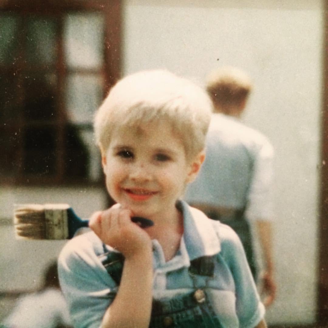 A young boy with a paintbrush, smiling — imagination at work.